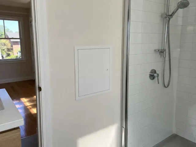 Small access panel in a tiled bathroom wall beside a shower in Marsfield